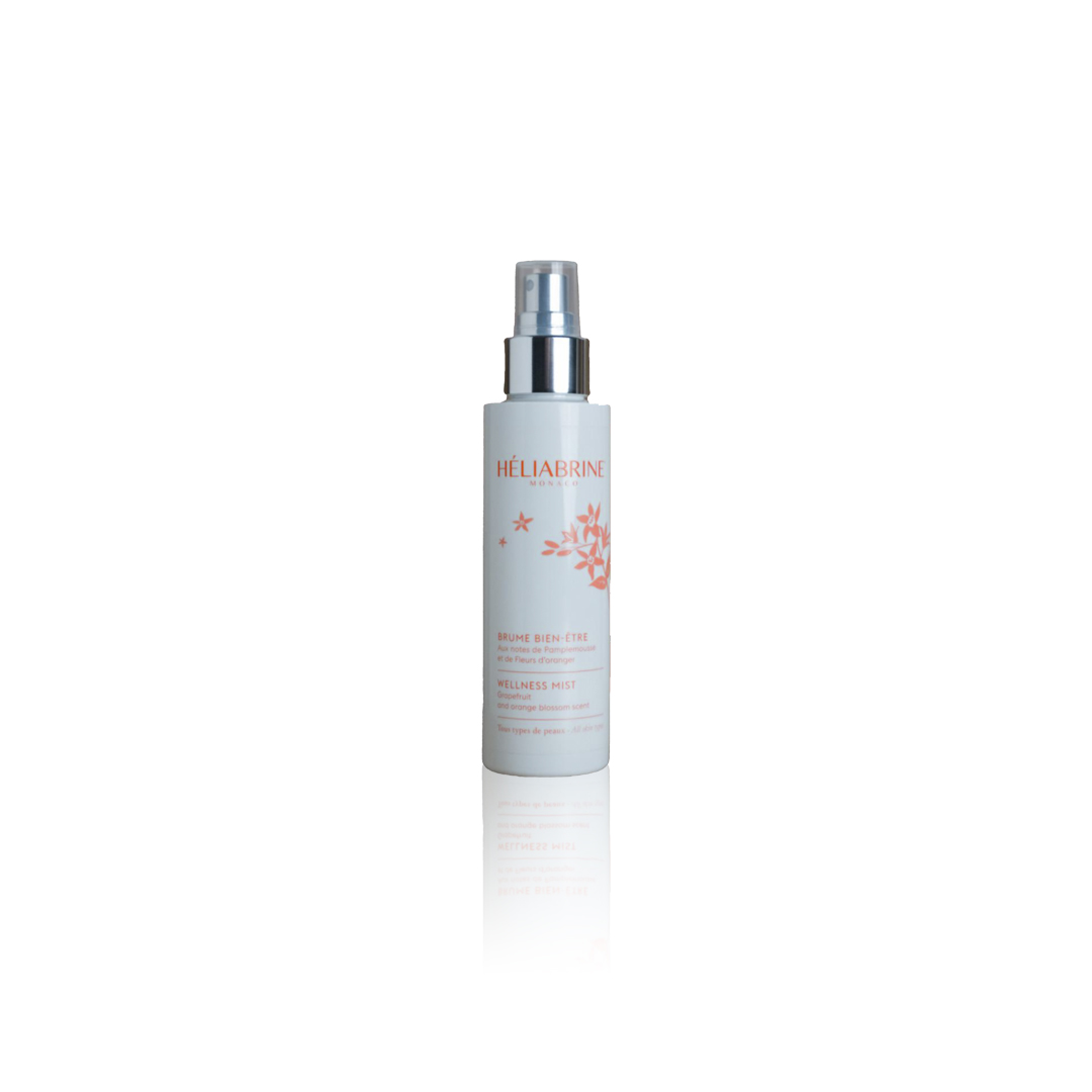 Na sliki je bela steklenička z razpršilnikom. Potiskana je z oranžnimi cvetovi in oranžnim napisom Héliabrine Wellness Mist.